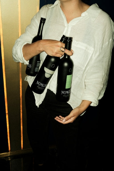A woman holding three bottles of Nomuss