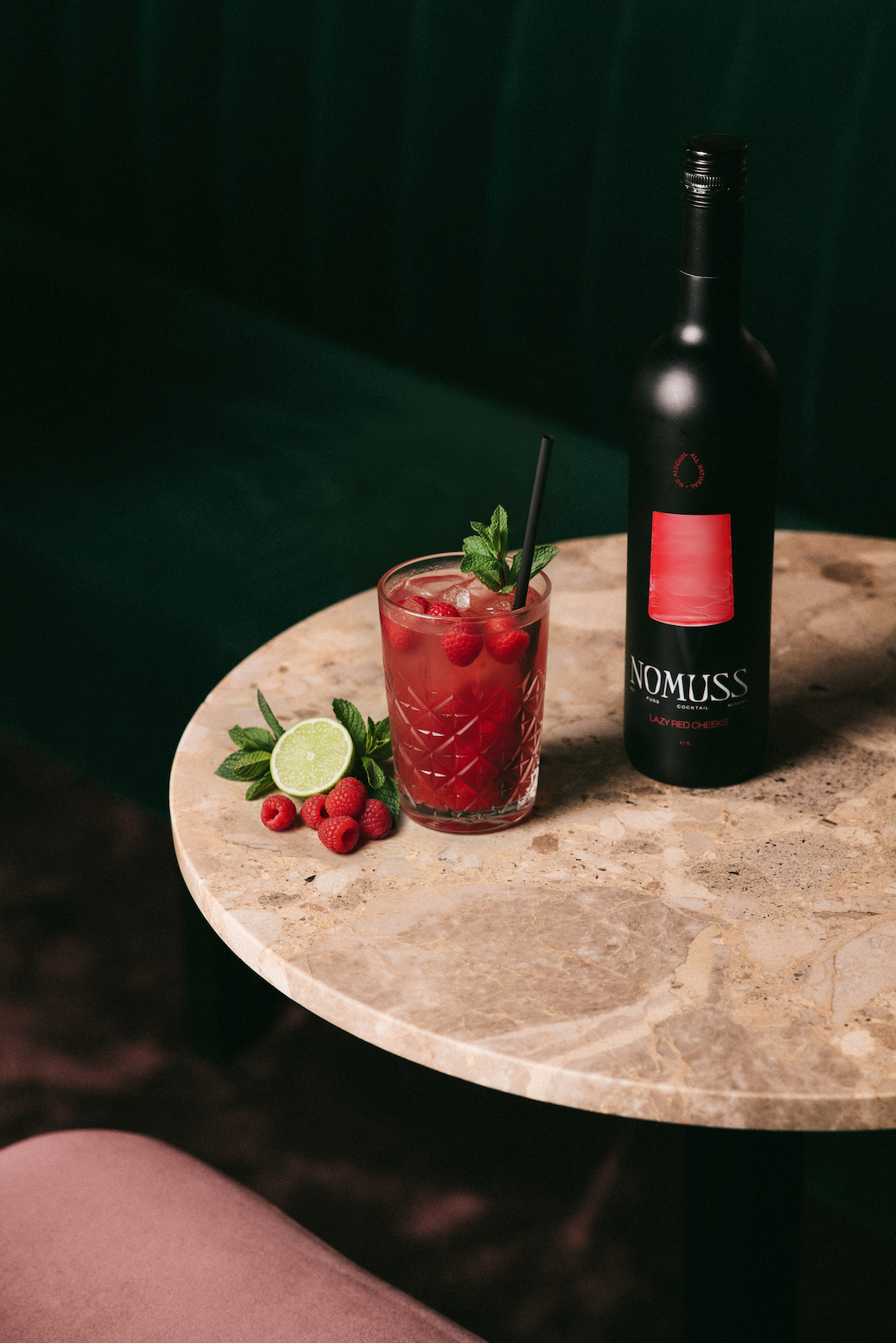Nomuss lazy red cheeks fles op een tafel met een lazy red cheeks cocktail. 